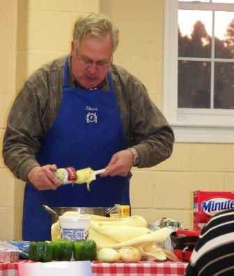 Chef Ken serving a colorful broccoli & cheese rice casserole